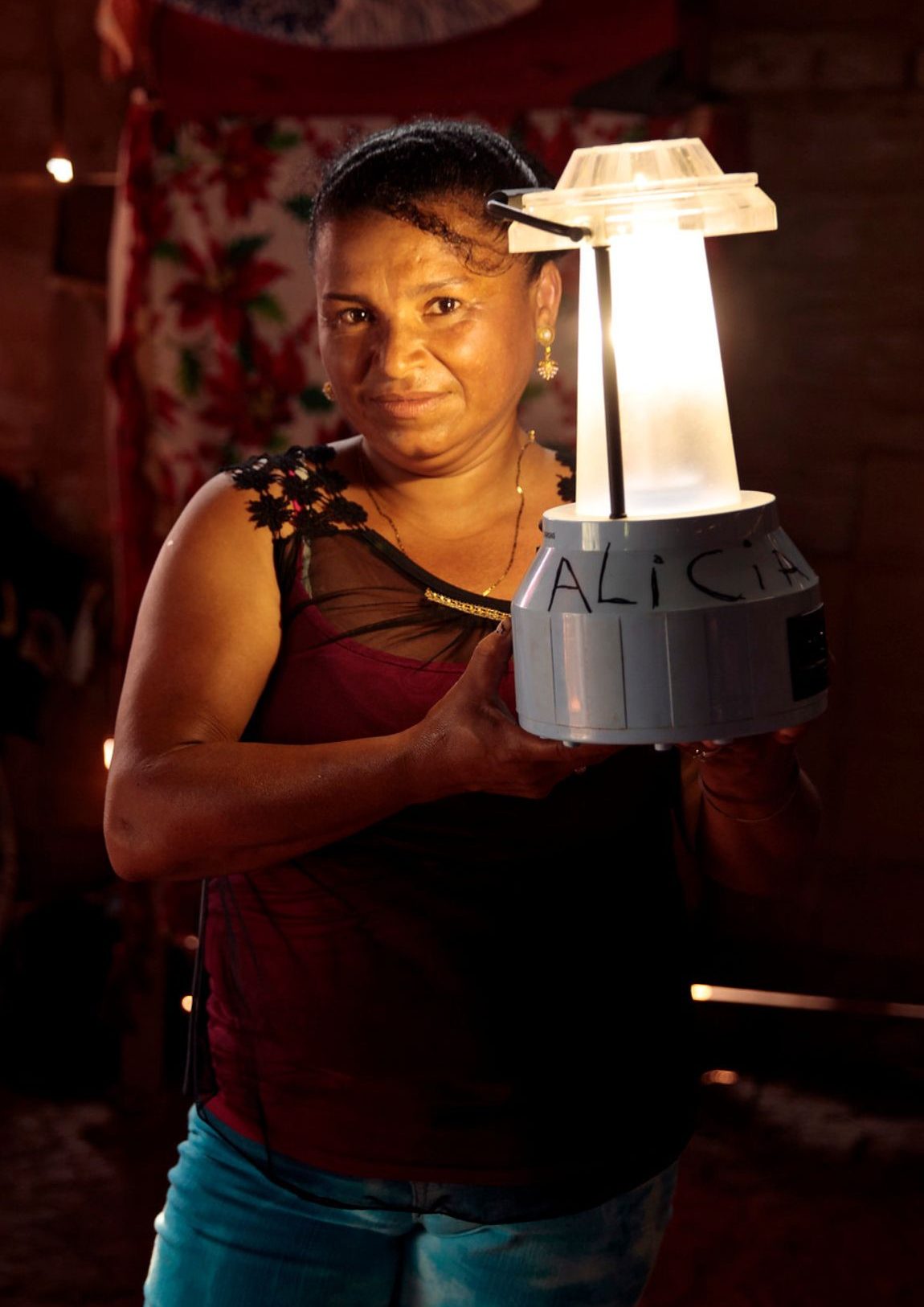 Martha präsentiert stolz eine leuchtende Solarlampe. - Als UN Women Friend und regelmäßige Spender*in ermöglichen Sie Frauen weltweit die Hilfe zur Selbsthilfe.