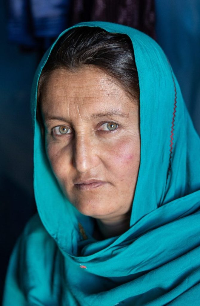 Afghanische Frau mit blauem Kopftuch schaut in die Kamera - UN Women hilft Frauen in Afghanistan