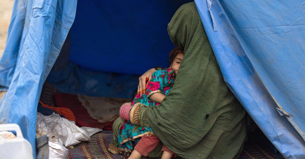 Afghanische Frau mit ihrer Tochter im Arm in einem blauen Zelt