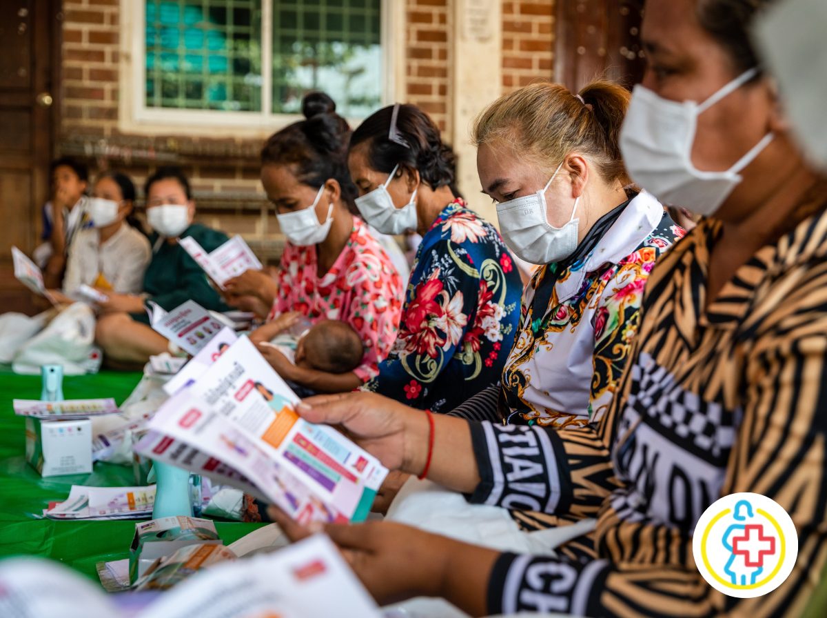 Frauen haben Gesichtsmasken auf und lesen eine Broschüre. UN Women - Kambodscha