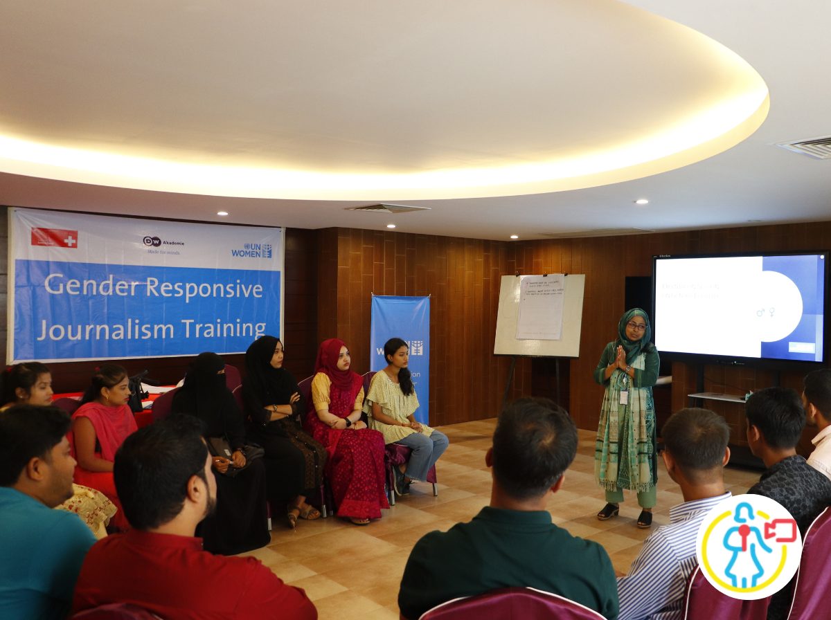 Eine Person hält einen Vortrag. Auf einem Plakat steht „Gender Responsive Journalism Training“ - UN Women gefördertes Projekt in Bangladesch