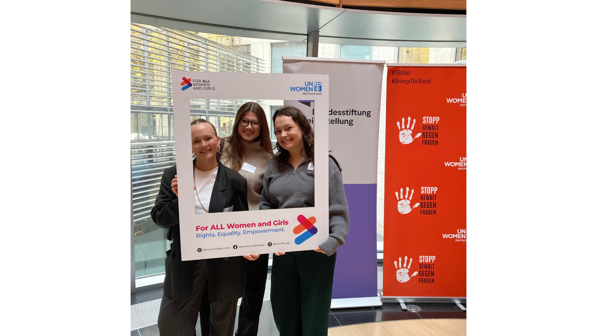 Three participants of the conference posing with a sign with the text