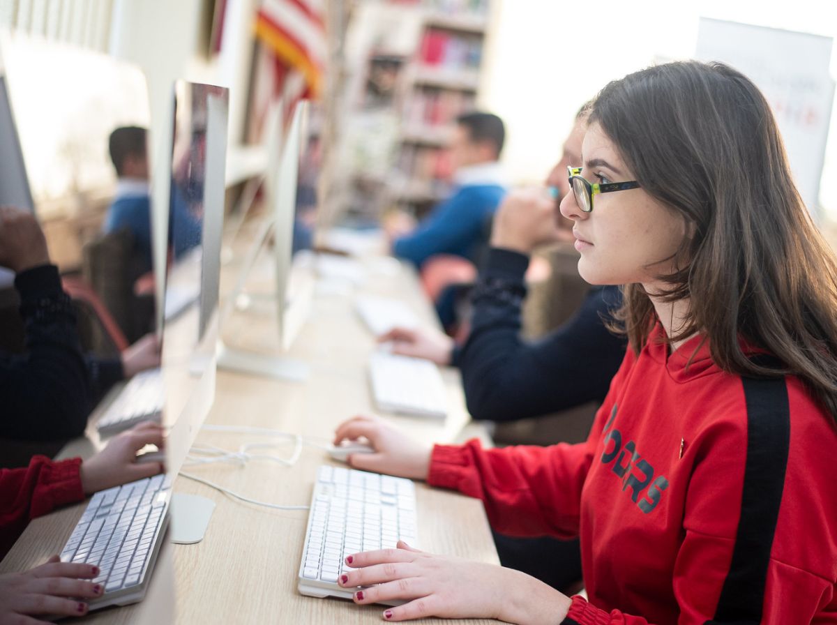 Junge Frau mit Brille sitzt vor einem Computer