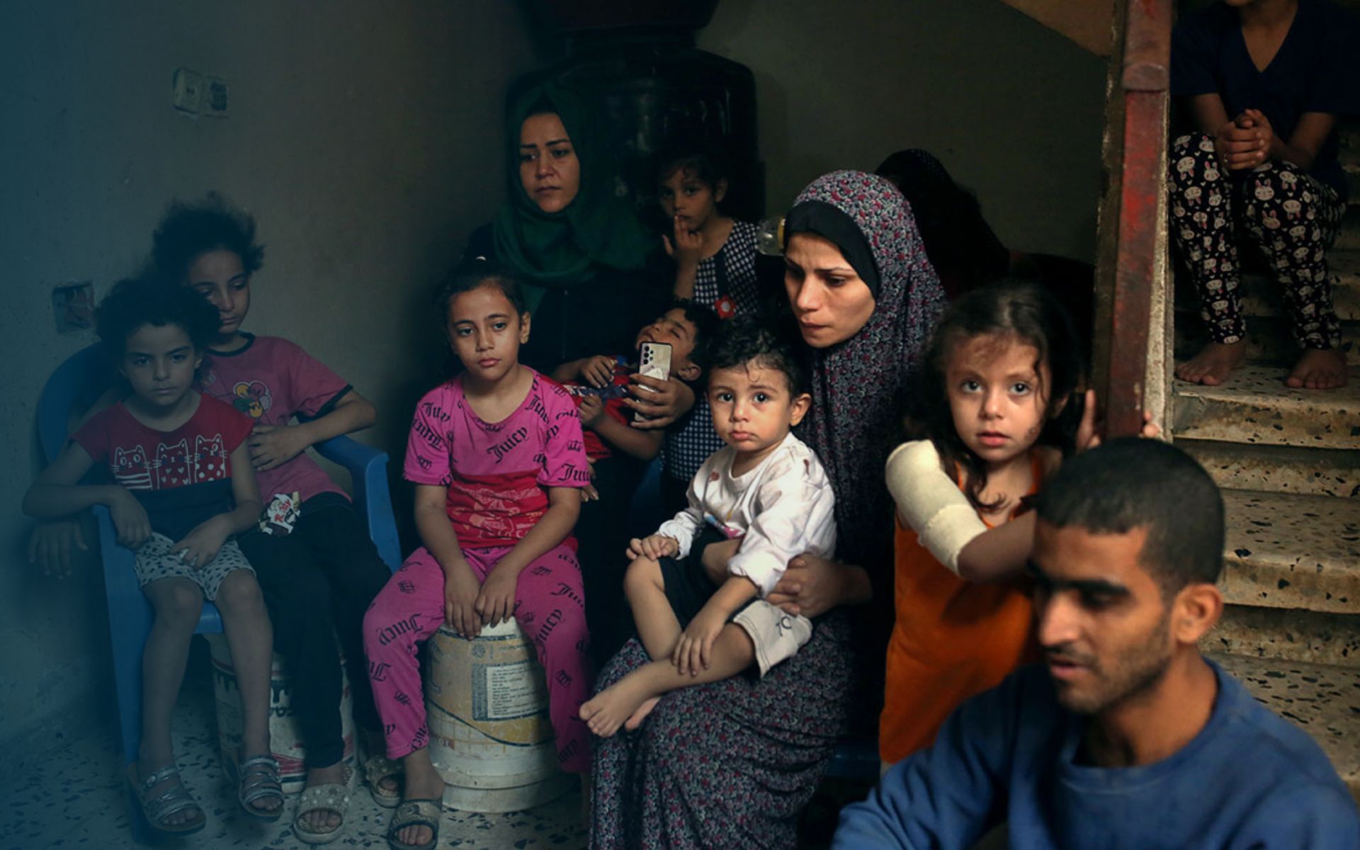 Frauen und Kinder sitzen im Treppenhaus mit besorgten Gesichtern - Feministischer Muttertag 2024