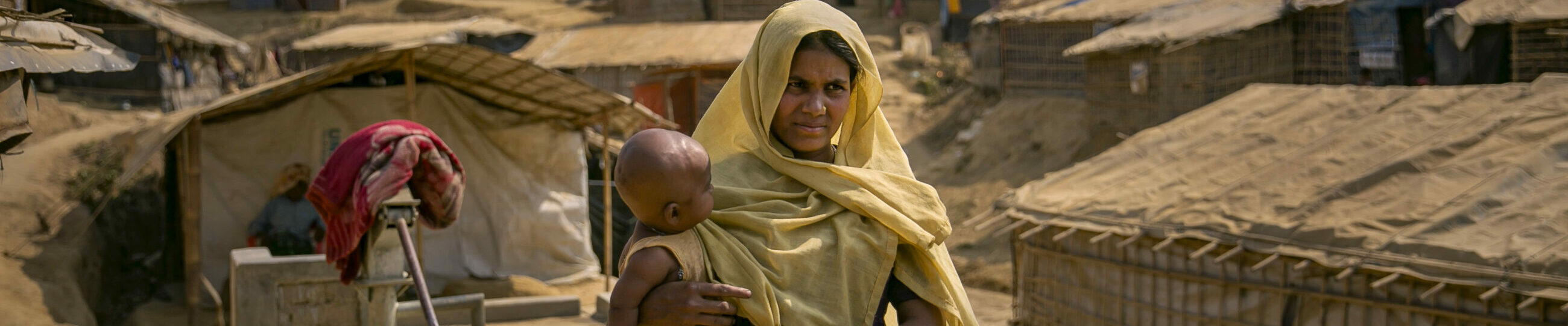 Eine Mutter mit ihrem Kleinkind auf dem Arm geht am 5. März 2018 an einer Wasserpumpe im Lager Balukhali vorbei.